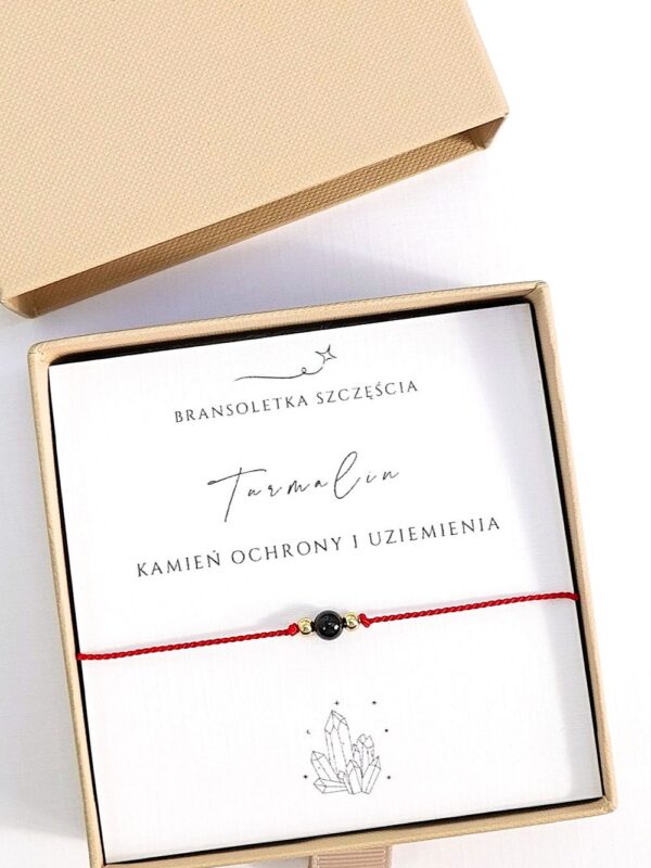 bransoletka z turmalinem na czerwonym sznurku w pudełku prezentowym.