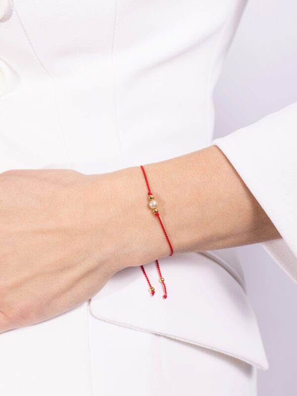 bransoletka z perłą na czerwonym sznurku na ręce