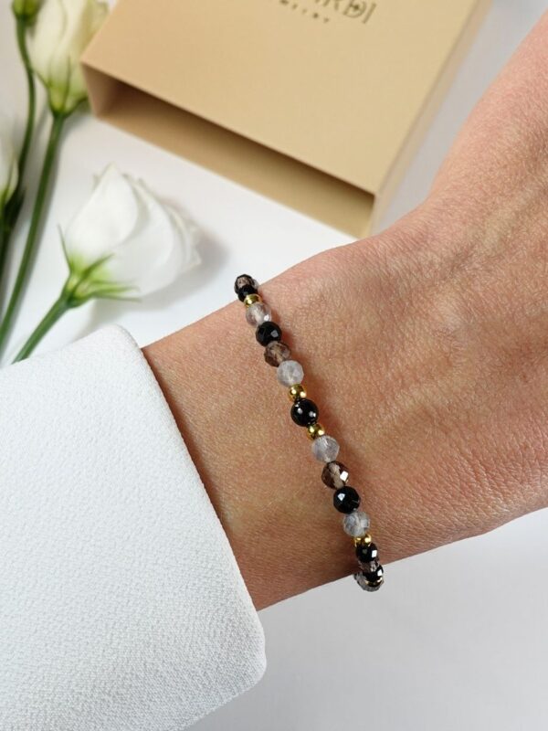 Bransoletka damska z czarnym turmalinem, talizman ochronny, na nadgarstku.