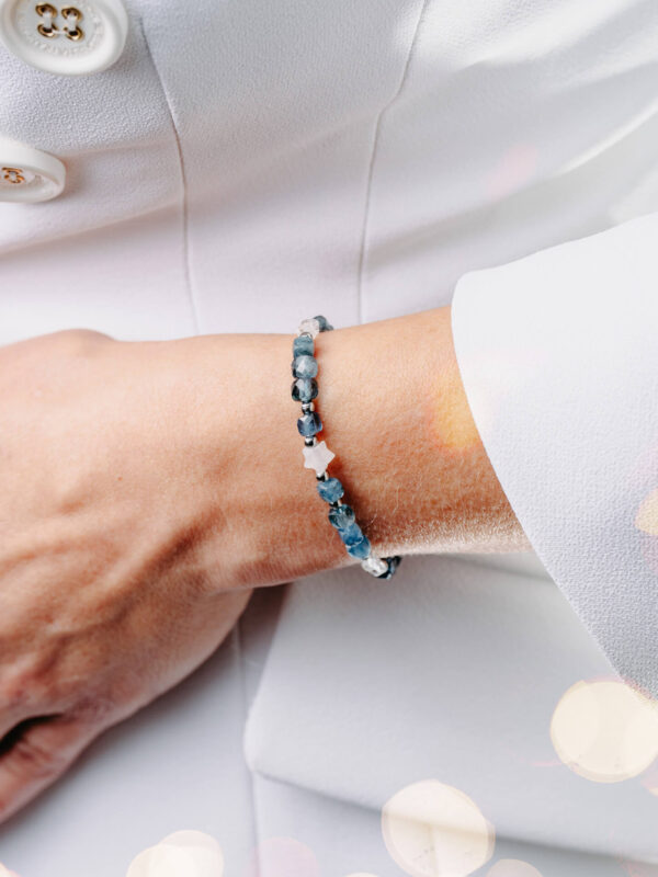 Bransoletka z ciemnego akwamarynu z kryształem górskim i gwiazdką na nadgarstku.