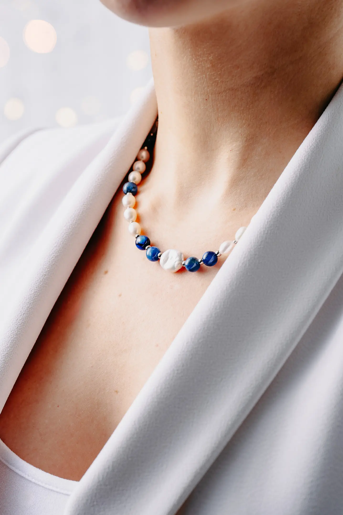 Naszyjnik z pereł naturalnych i kianitu – kamienia półszlachetnego, na szyi.